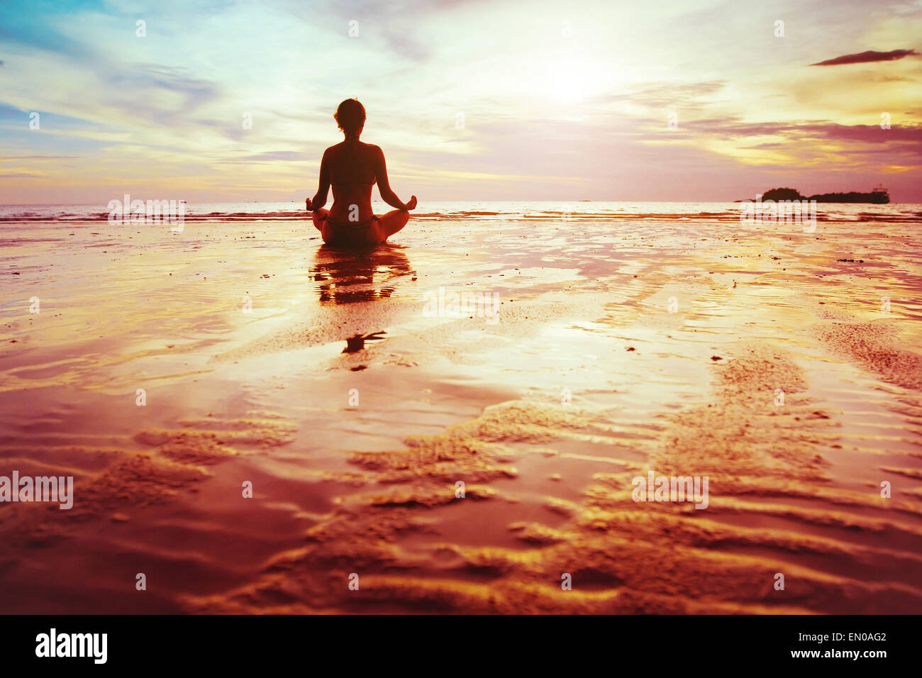 Aufklärung, Silhouette der Frau praktizieren Yoga am Strand Stockfoto