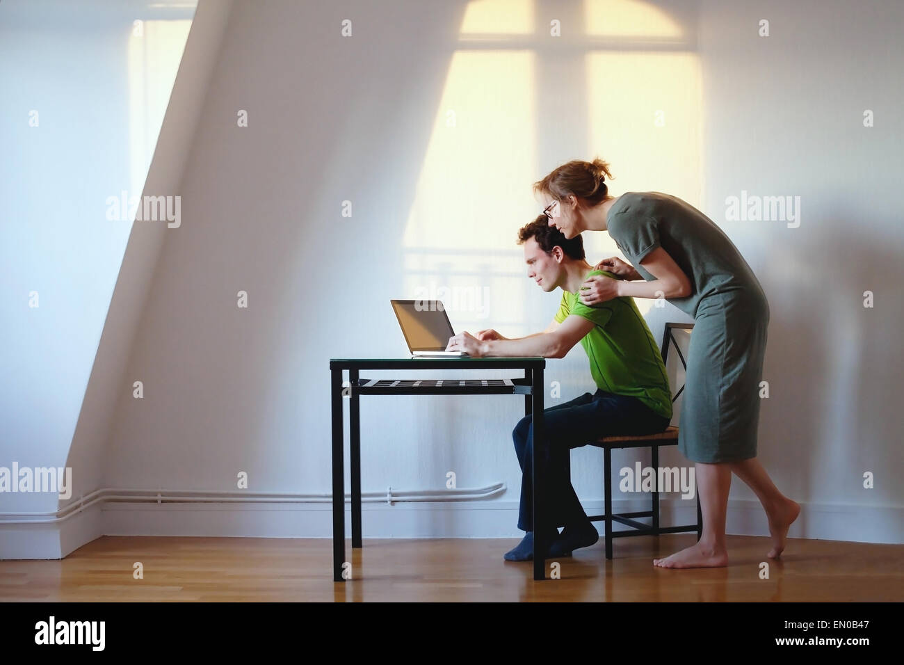 junges Paar auf der Suche auf dem Laptop in ihrem Haus in hellen Innenraum Stockfoto