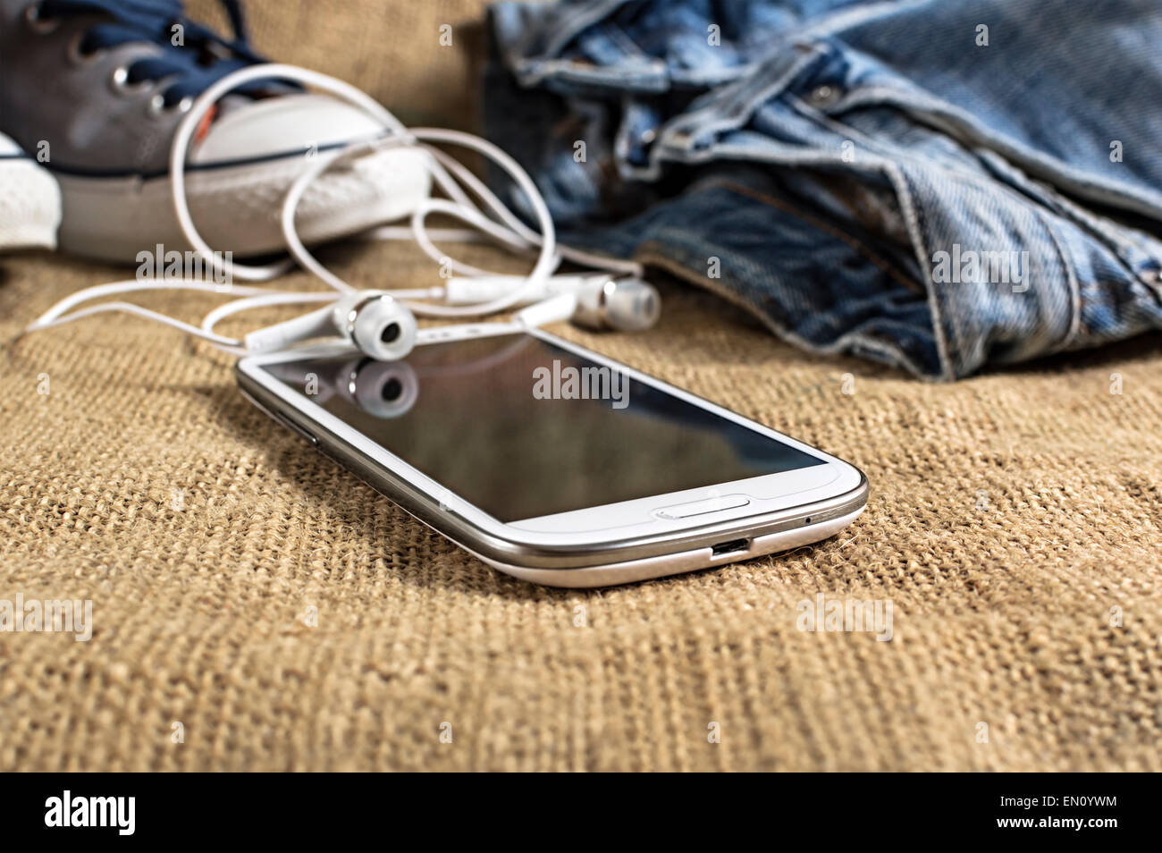 Smartphone auf einer Tischdecke mit Hosen und Turnschuhe. geringe Schärfentiefe. Stockfoto