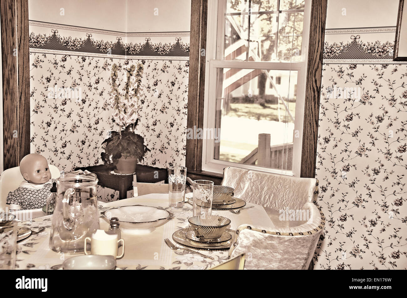 Alte Puppe in einen Hochstuhl in einer Retro-Küche. Stockfoto