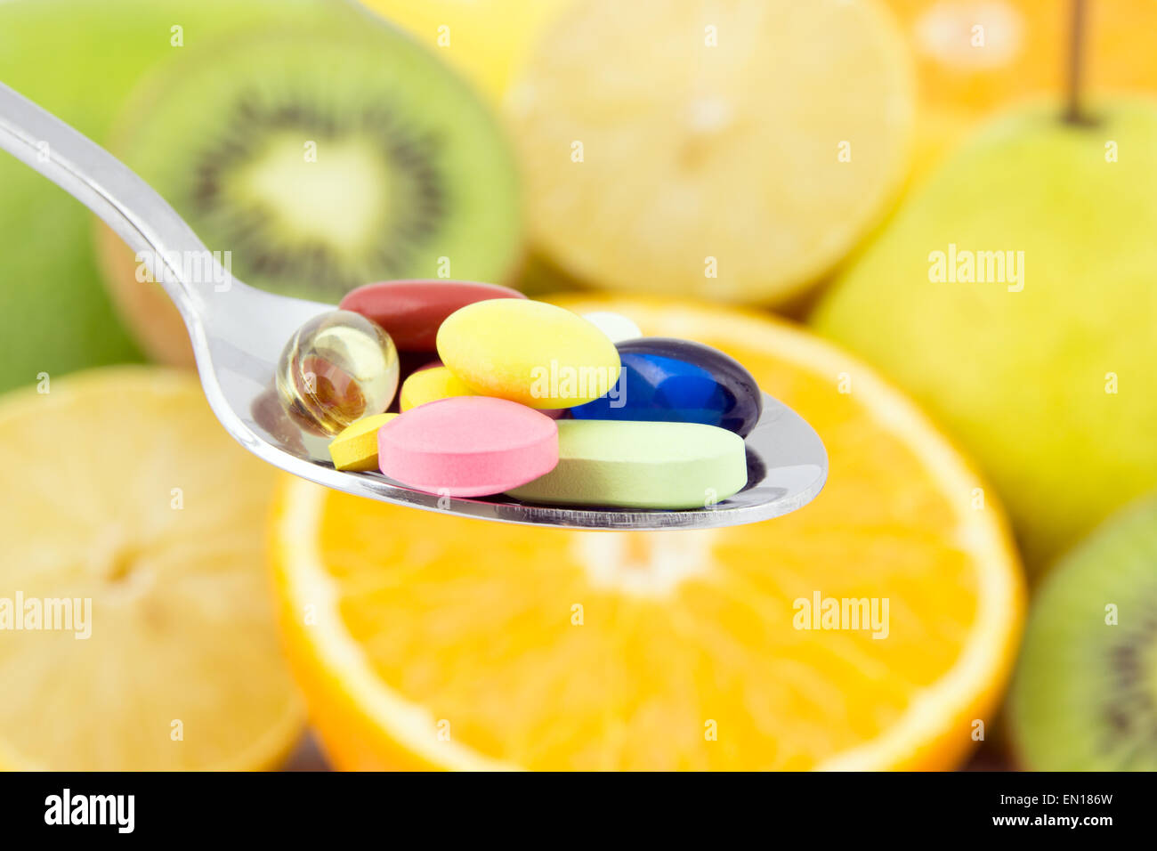 Bunte Pillen auf einem Löffel gegen fruchtigen Hintergrund Stockfoto