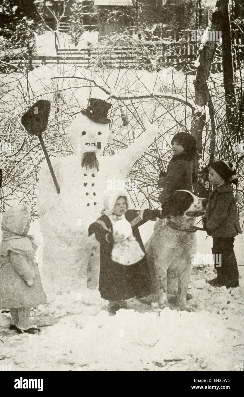 In diesem frühen 1900er Jahre Foto stehen Kindern und einem Hund einen neugebildeten Schneemann. Stockfoto