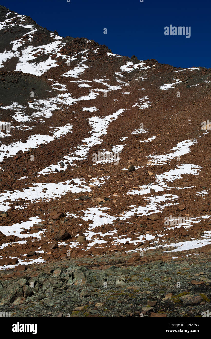 Piz Nair Schweiz Engadin Alpen Scuol Berghang mit losen roten und grünen Steinen und Schneeflecken Stockfoto