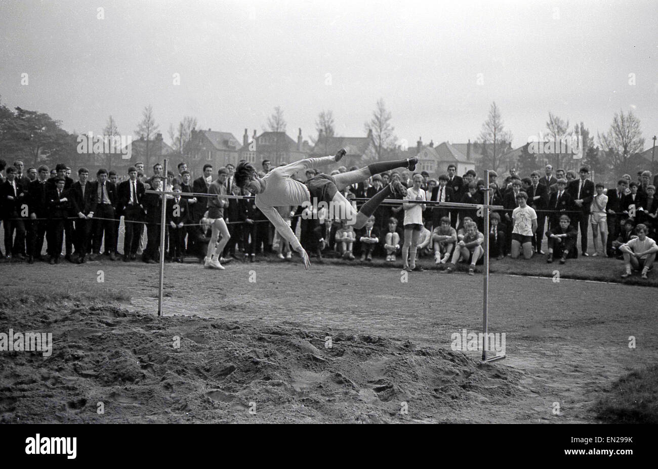 1960er Jahren Geschichtsbild vom Schulsporttag eines Schülers versuchen im Hochsprung mit der Straddle oder Western roll Technik. Stockfoto