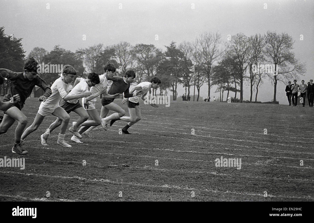 1960er Jahren Geschichtsbild vom Schulsporttag der Schüler läuft ein 100-Meter-Sprint-Rennen außerhalb auf dem Rasen. Stockfoto