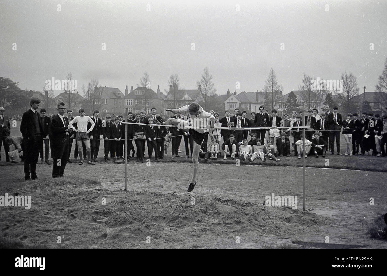 historische, eine Schule Sport-Tag, der 1960er Jahre Rollen Schüler versuchen den Hochsprung mit dem Straddle oder westliche Technik. Stockfoto