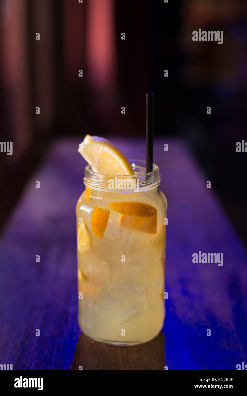 Limonade cocktail im Glas mit Strohhalm auf blau und lila Hintergrund Stockfoto