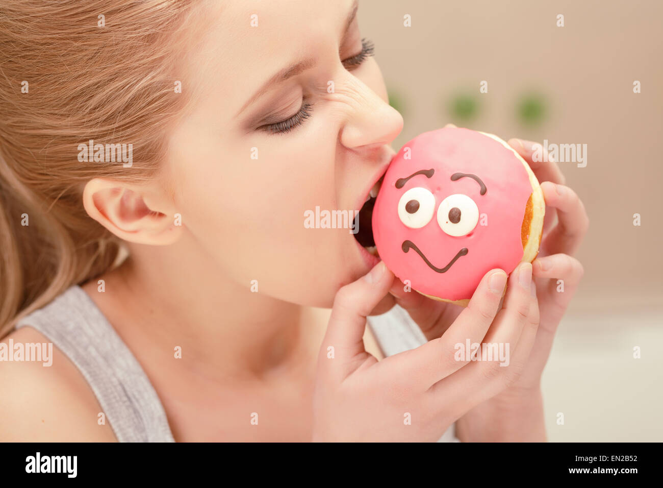 Junge Frau beißt einen rosa donut Stockfoto