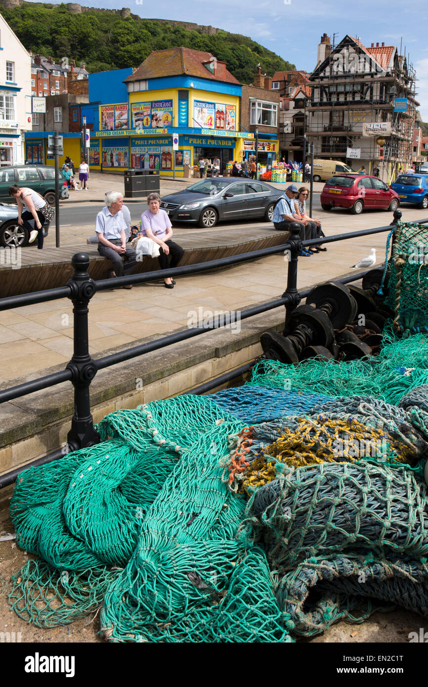 Großbritannien, England, Yorkshire, Scarborough, Sandside, Besucher saßen auf Bank durch Fischernetze auf Arbeit Kai Stockfoto