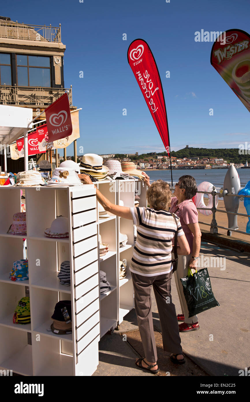 Großbritannien, England, Yorkshire, Scarborough, zwei mittleren Alters Frauen betrachten Hüte vor Strand Zubehör Shop Stockfoto