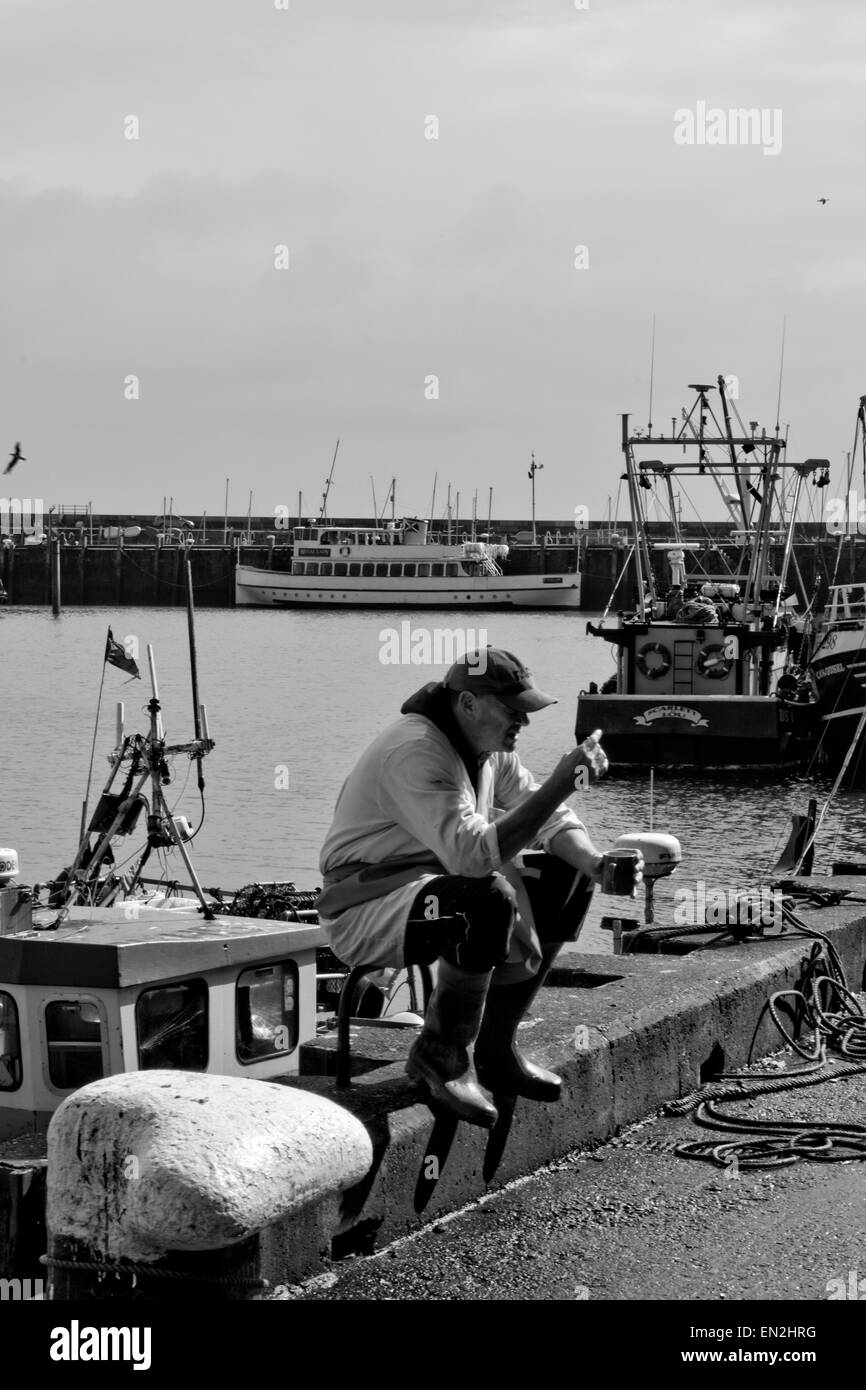 schwarz weiss dokumentarische Anzeigenbild zeigt einen Fischer sein Mittagessen an einem warmen Tag in Scarborough genießen Stockfoto