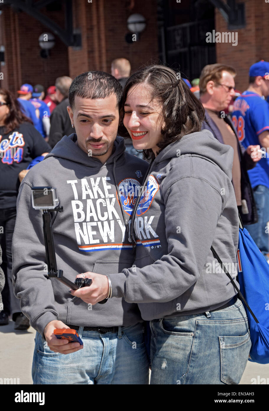 Ein paar auf die Mets Spiel posieren für Selfies mit zwei Kameras, eine auf einem Selfie Stick im Citi Field Stadium in Flushing, Queens genommen. Stockfoto