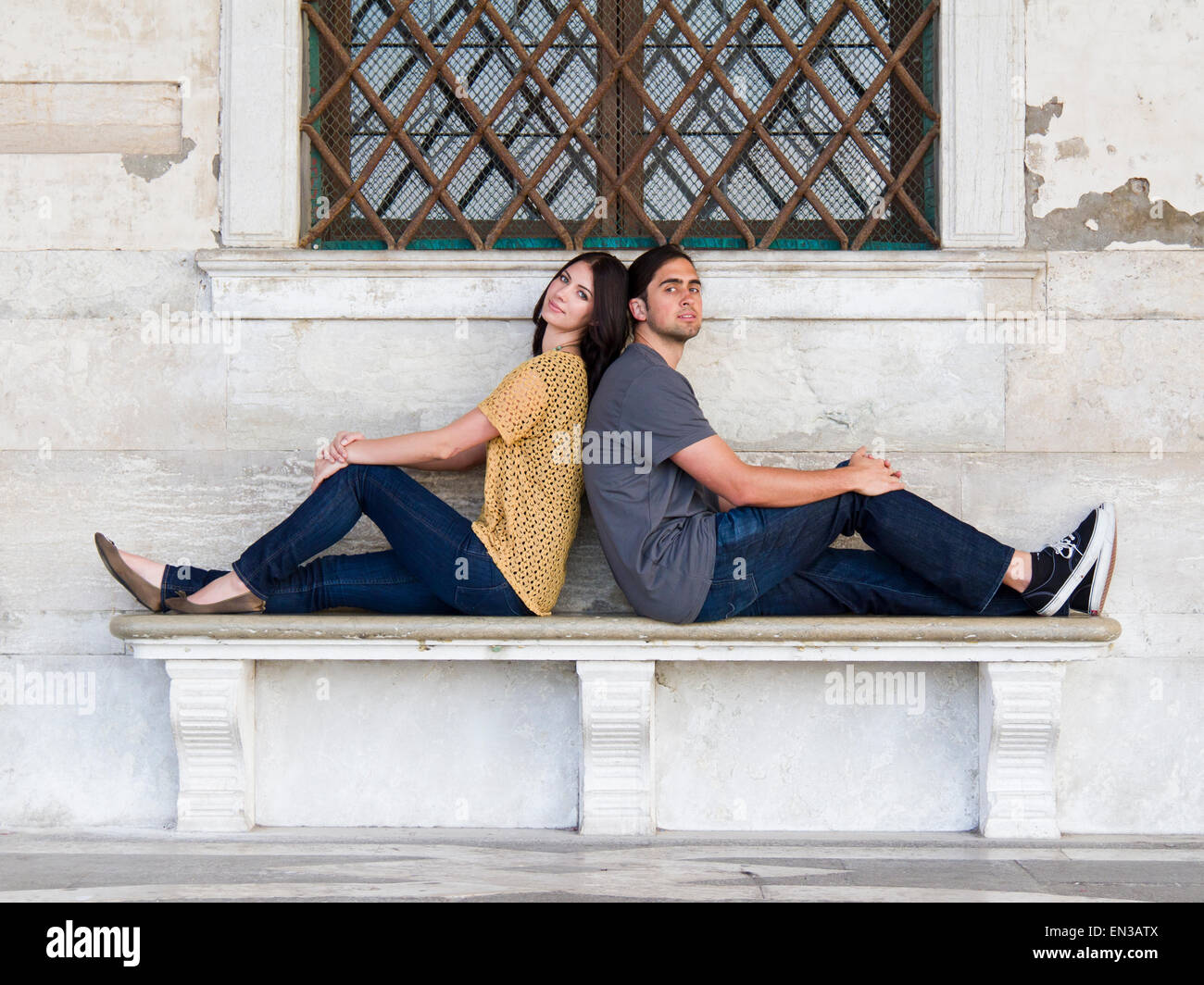 Italien, Venedig, junges Paar sitzen Rücken an Rücken auf Bank Stockfoto