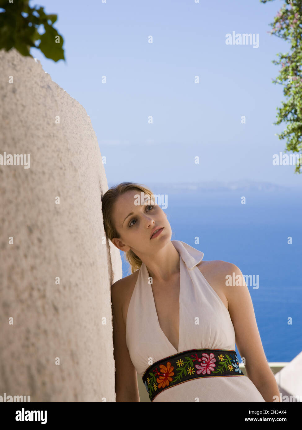 Frau lehnen an der Wand im Freien mit blauen Himmel und Wasser Stockfoto