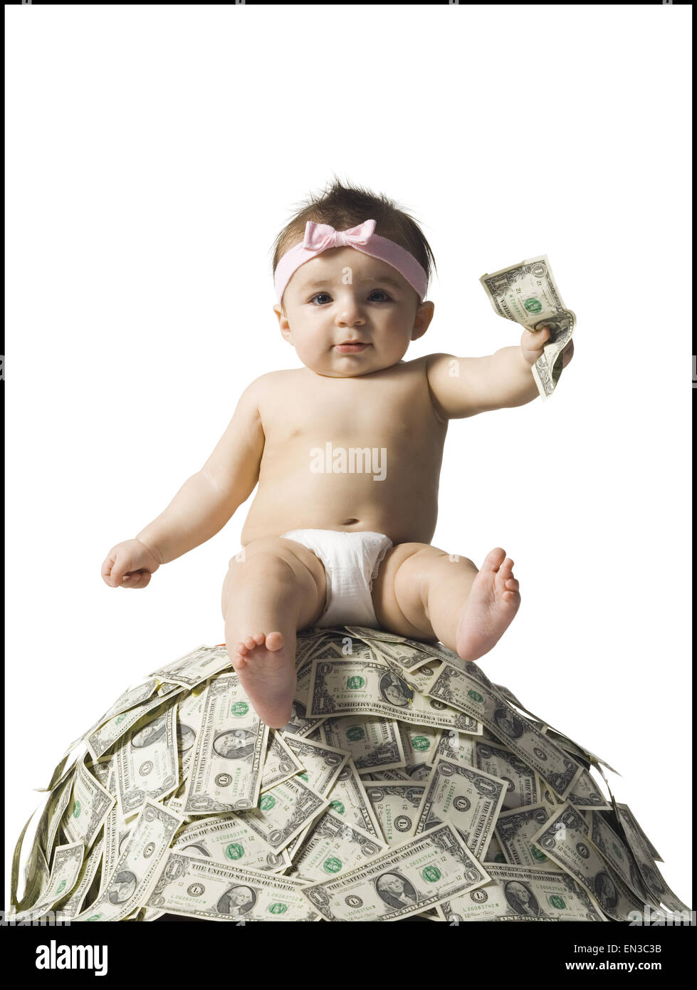 Babymädchen sitzen auf Haufen von US-Währung Stockfoto