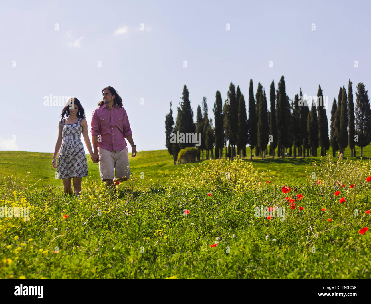 Italien, Toskana, Val D'Orcia, junge Paare, die auf Wiese Stockfoto