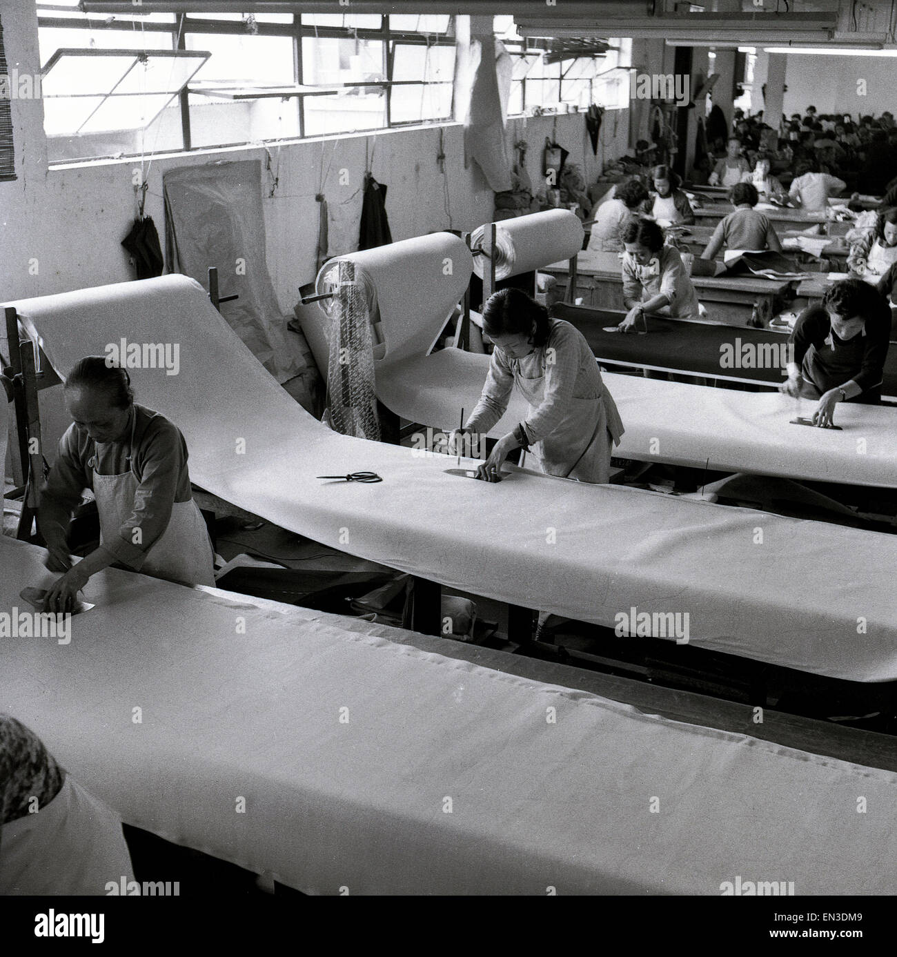 1950er Jahre historische, weibliche chinesische Arbeiter in der Fabrik zerschneiden Großrollen Stoff, Kleidung, Hong Kong zu machen. Stockfoto