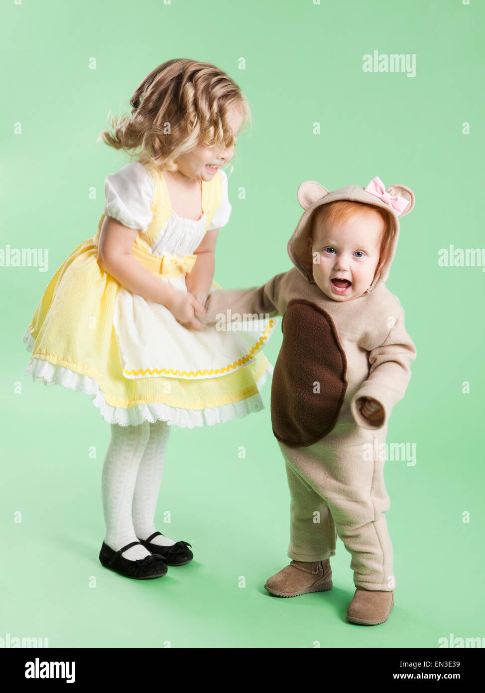 Mädchen (2-3) als Goldilocks mit Babymädchen (12-17 Monate) als Bär für Halloween Stockfoto