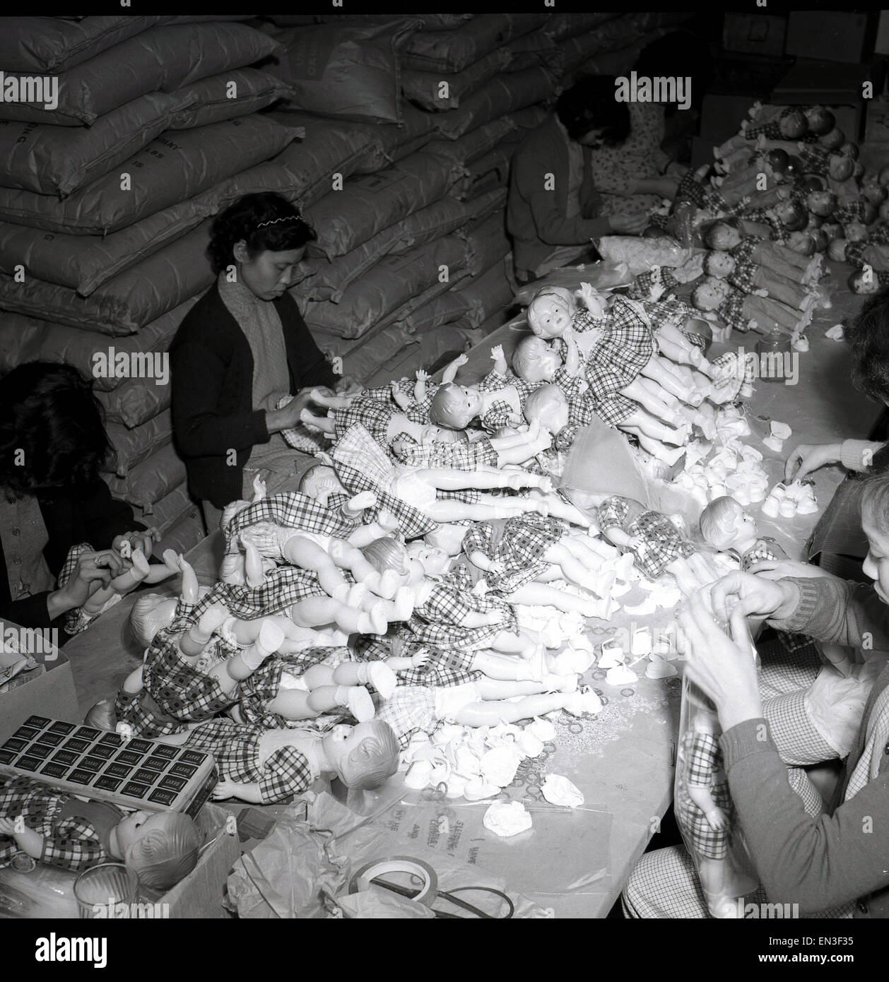In den 1950er Jahren, historisch, hongkong, chinesische Arbeiterinnen in einer Fabrikeinheit, die sich aufmachen und Plastikspielzeugpuppen zusammenstellen. Es war nicht lange nach dem Ende des 2. Weltkriegs, dass harter Kunststoff das Material für Puppenmacher wurde, da er langlebig war und geformt werden konnte. In den 50er und 60er Jahren wurde Hongkong bald zum Epizentrum der Spielzeugproduktion, mit Tausenden von kleinen Produktions- und Produktionseinheiten, wie sie hier zu sehen sind, in Kellern und oberen Etagen von Gebäuden. Stockfoto