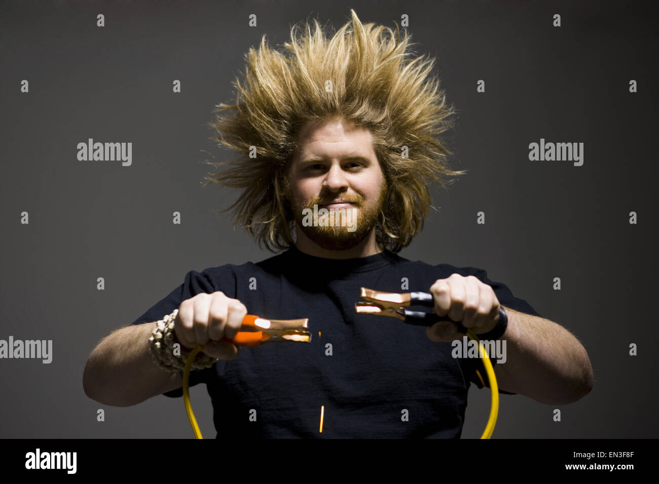Mann mit verrückten Haaren halten Starthilfekabel Stockfoto