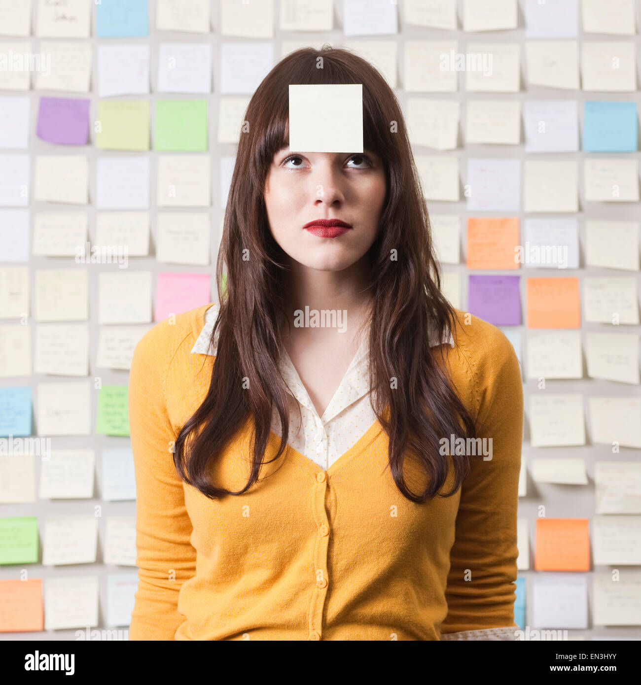 Studioaufnahme der jungen Frau, die bei Post-It auf Stirn beachten Sie Stockfoto