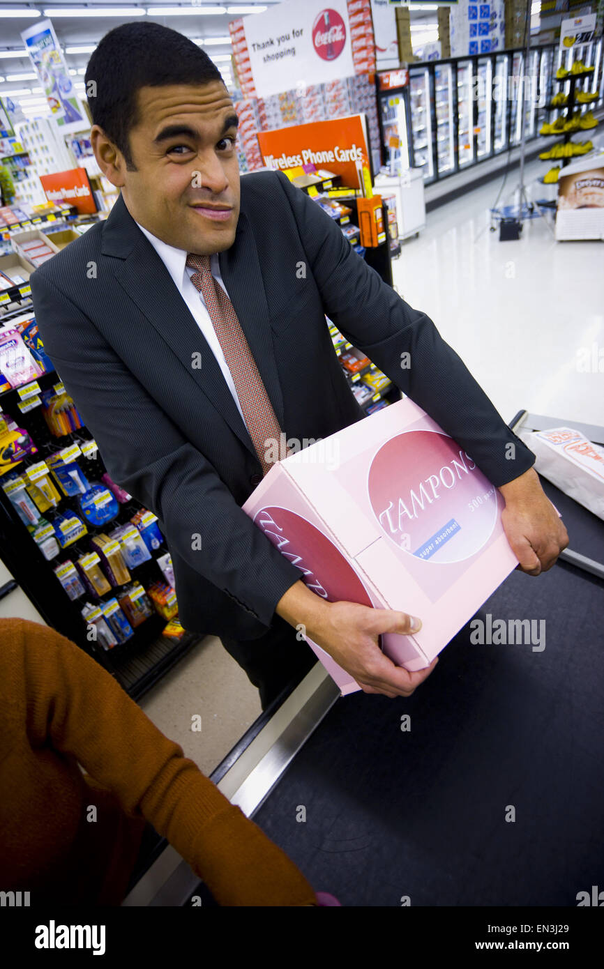 Mann an der Supermarkt Kasse mit Schachtel Tampons und zwei Frauen Stockfoto