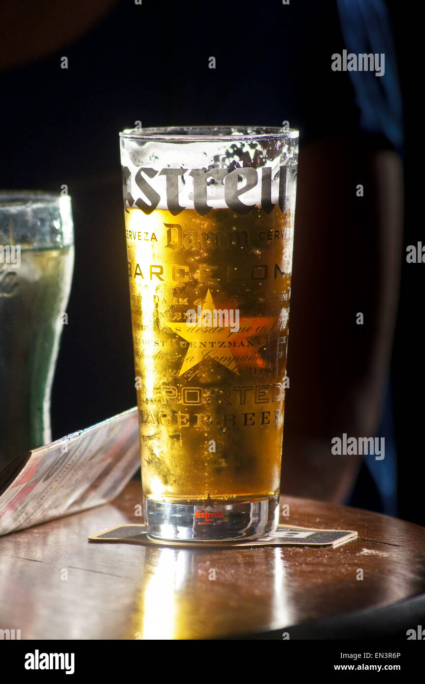 Eine gedruckte pint Glas Estrella Damm Spanisch Lagerbier mit  Hintergrundbeleuchtung eine Leiste am Freimaurerischen Arme, Kirkcudbright,  Schottland, pub Tabelle getränke Gläser Stockfotografie - Alamy