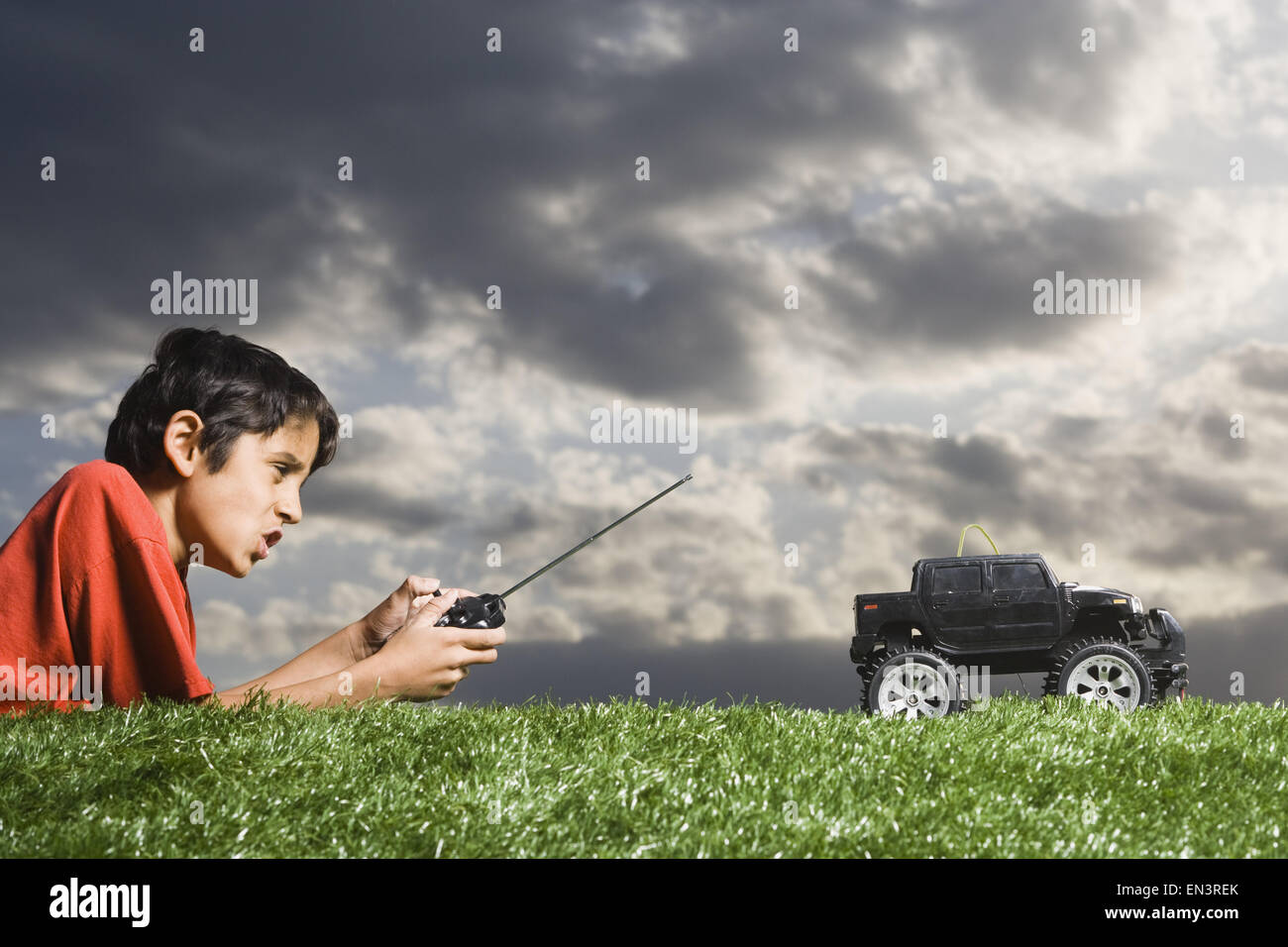 Jungen spielen mit remote gesteuerten LKW im Freien auf dem Rasen an bewölkten Tag Stockfoto