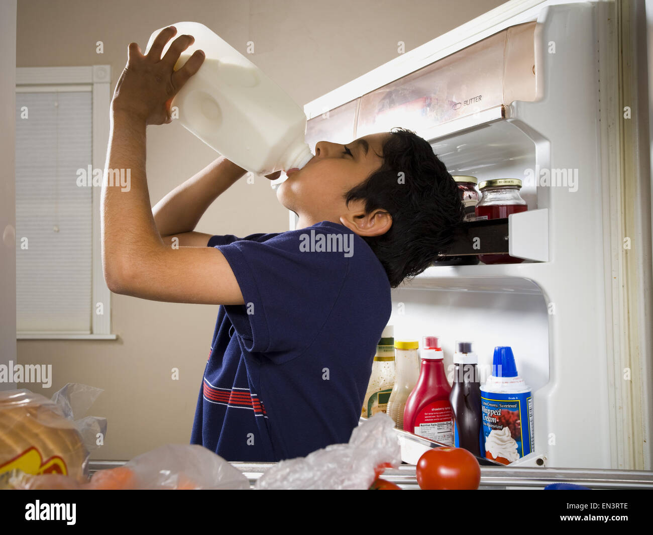 Junge Konsummilch aus Krug im Kühlschrank Stockfoto