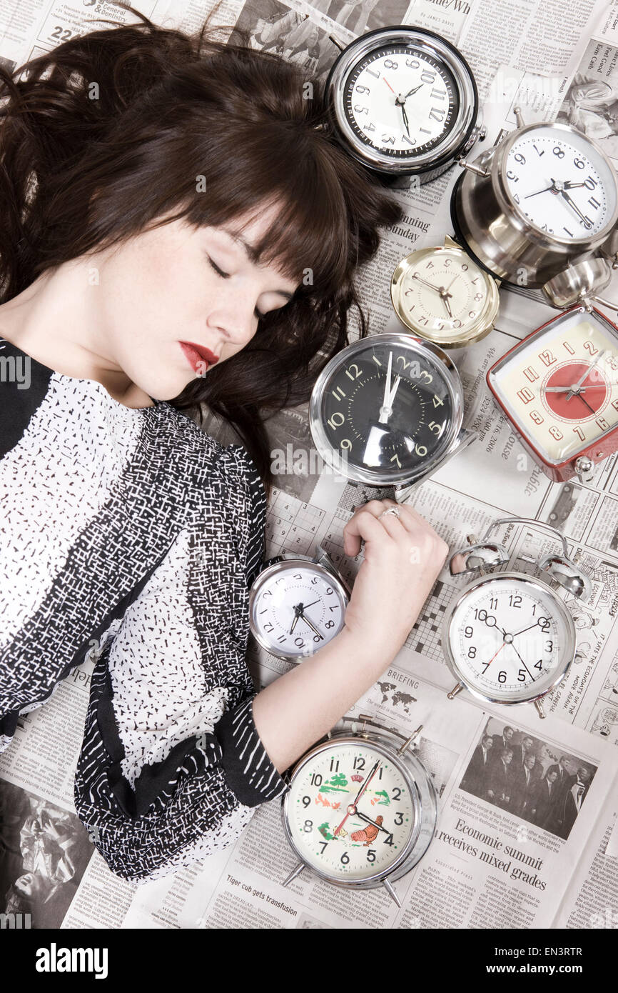 Studioaufnahme der jungen Frau schläft mit Wecker Stockfoto