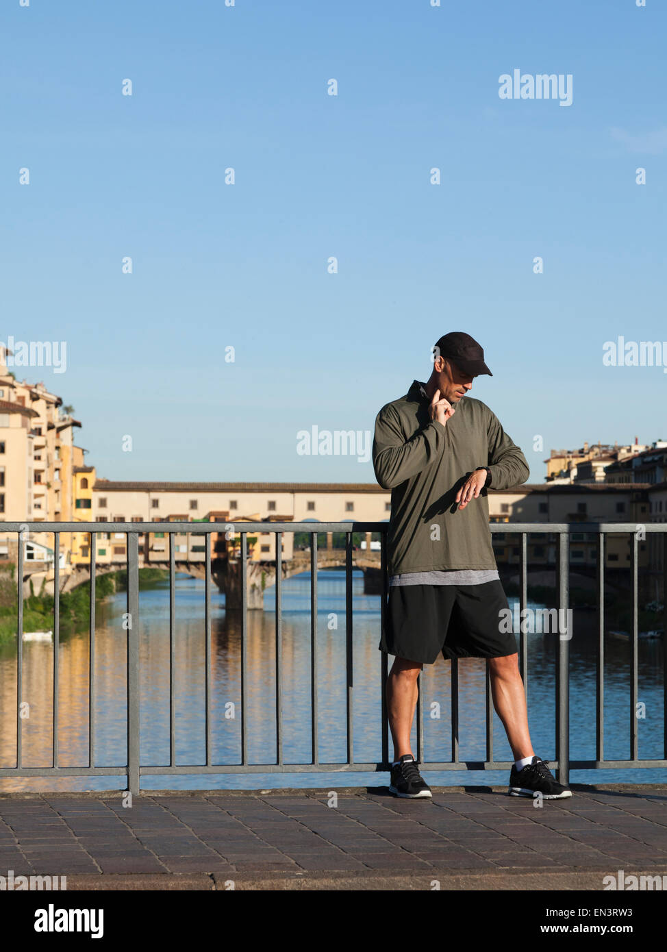 Italien, Florenz, Mann, die Überprüfung von Puls auf Brücke über Fluss Arno Stockfoto