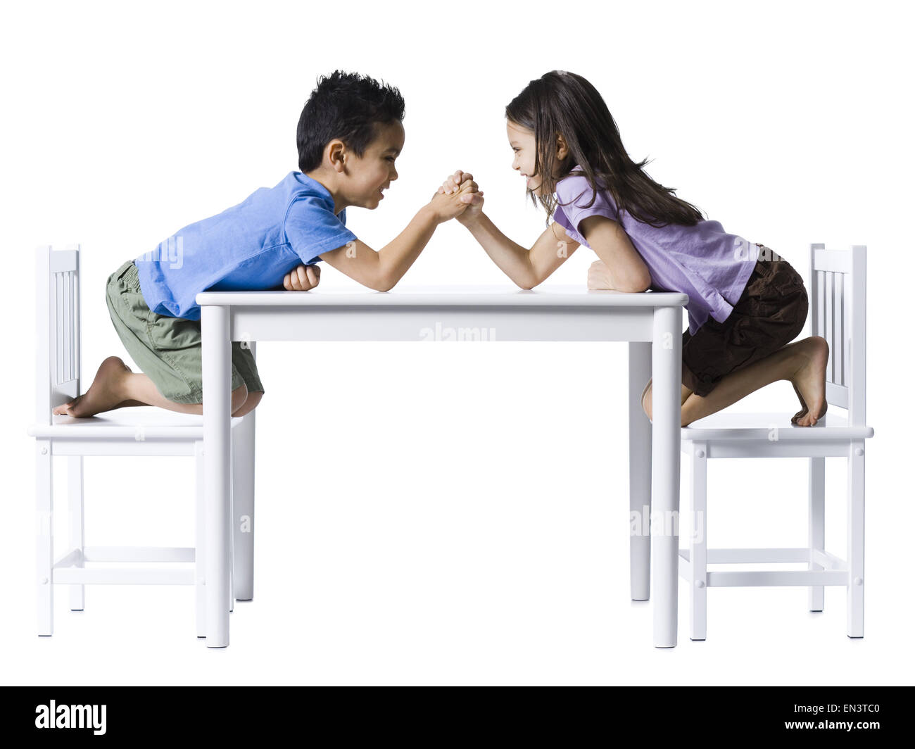 Jungen und Mädchen sitzen am Tisch Armdrücken Stockfoto