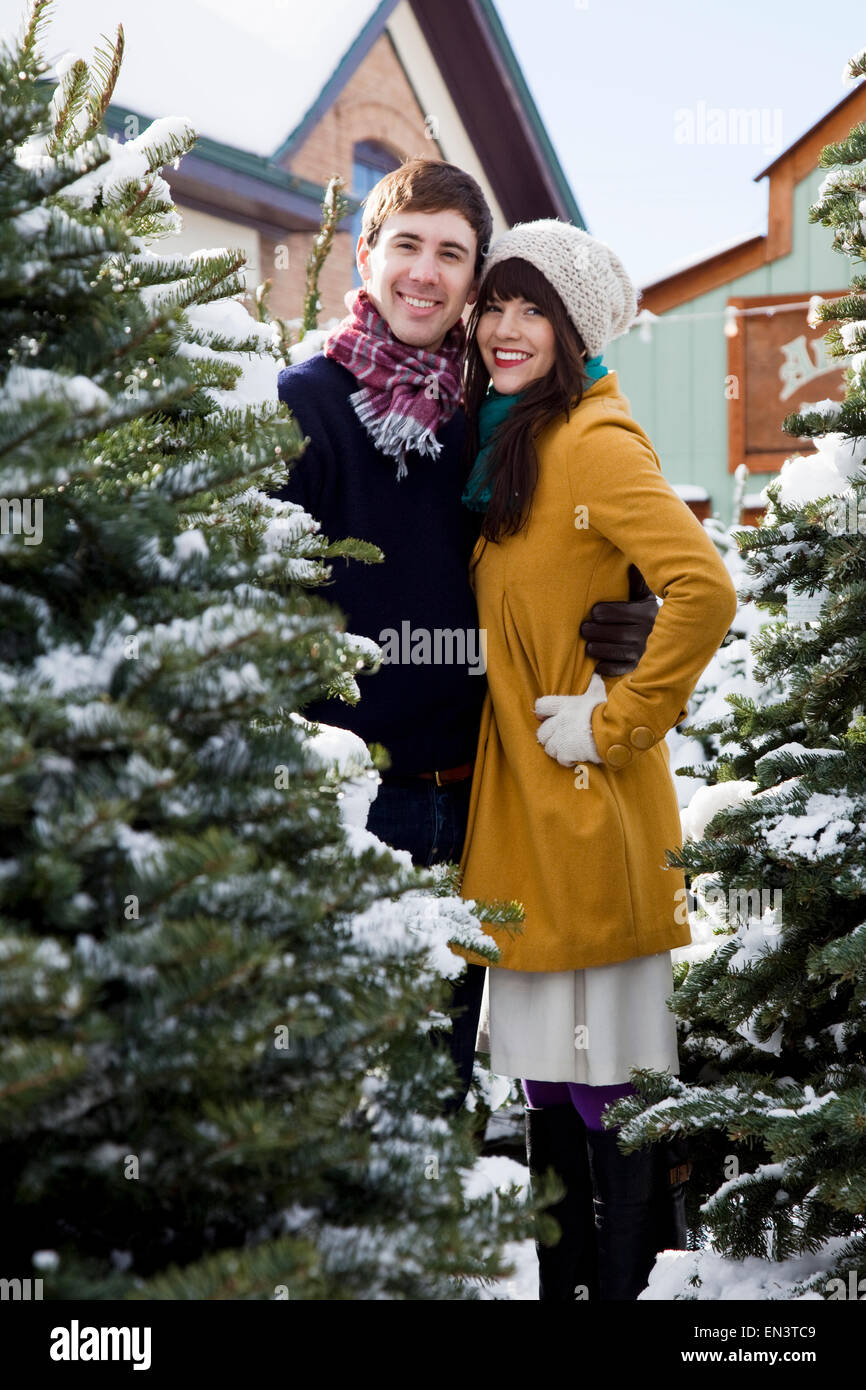 junges Paar immer einen Weihnachtsbaum im Schnee Stockfoto