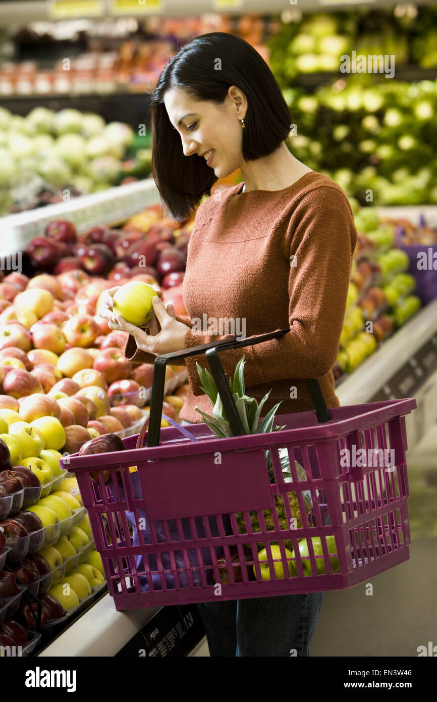 Frau mit grünen Äpfeln im Supermarkt mit Einkaufskorb Stockfoto