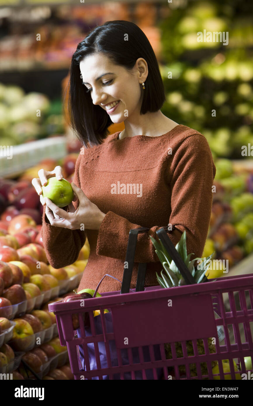 Frau mit grünen Äpfeln im Supermarkt mit Einkaufskorb Stockfoto