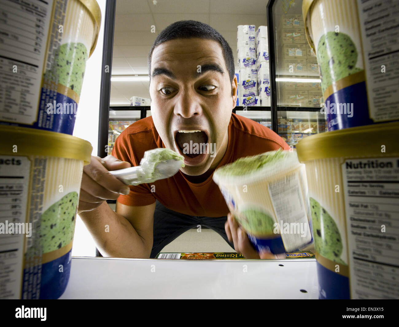 Mann isst Eis im Supermarkt Stockfoto