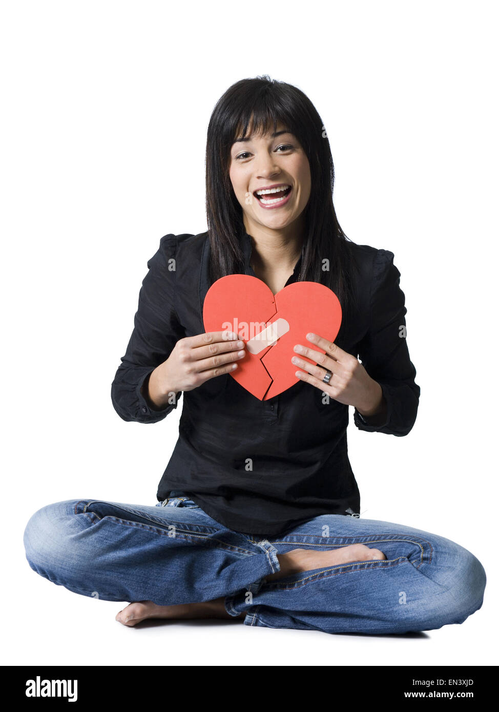 Frau sitzt Schneidersitz mit lächelnden mended rotes Herz Stockfoto