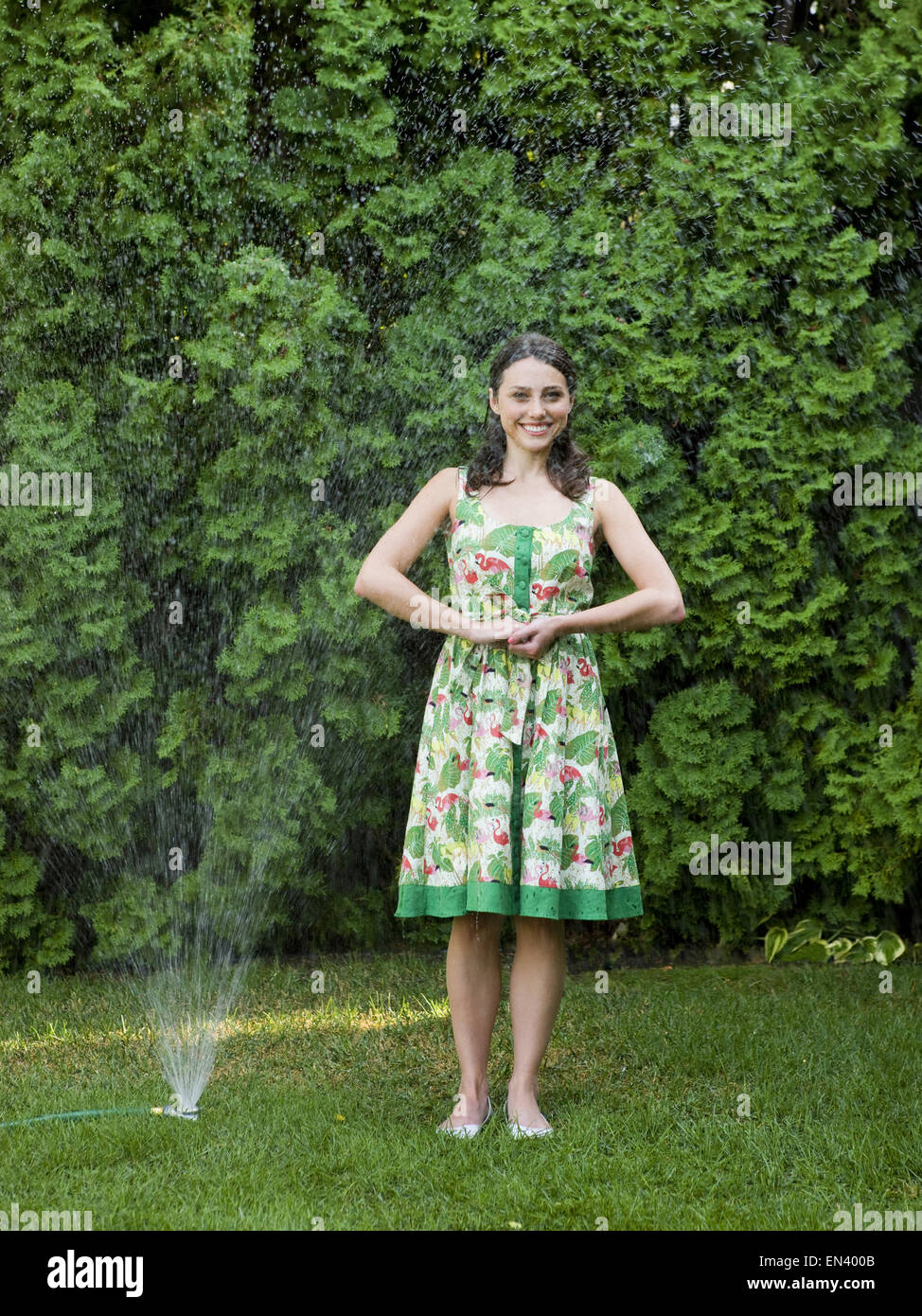 Frau in einem Kleid steht in der Sprinkler Stockfoto