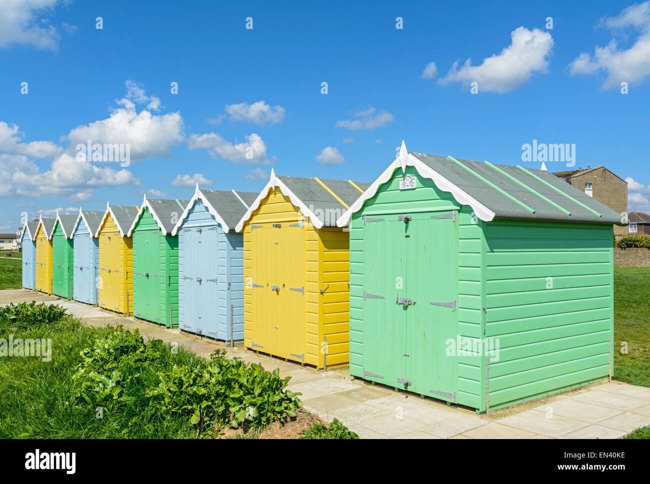 Bunte frisch gestrichene Strandhütten mit blauem Himmel an einem sonnigen Tag im Vereinigten Königreich. Stockfoto