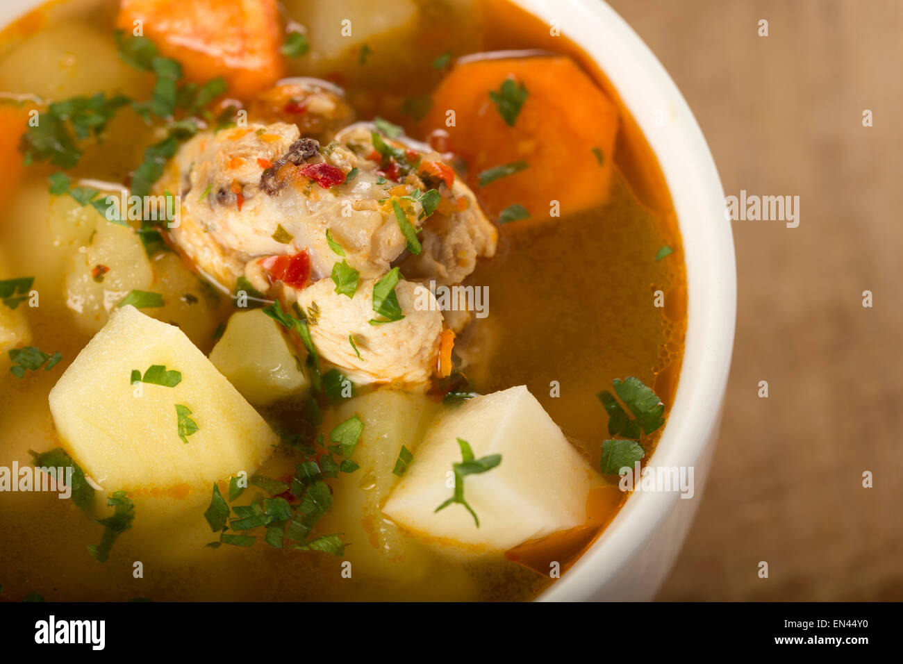 Hausgemachte Hühnersuppe in einer weißen Schüssel auf einem Holztisch Stockfoto