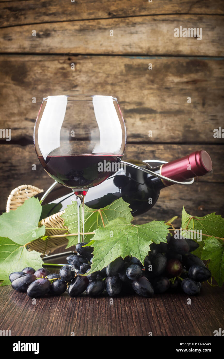 Weingut Hintergrund. Weinglas mit Flasche Rotwein und Cluster Traube auf Holztisch Stockfoto