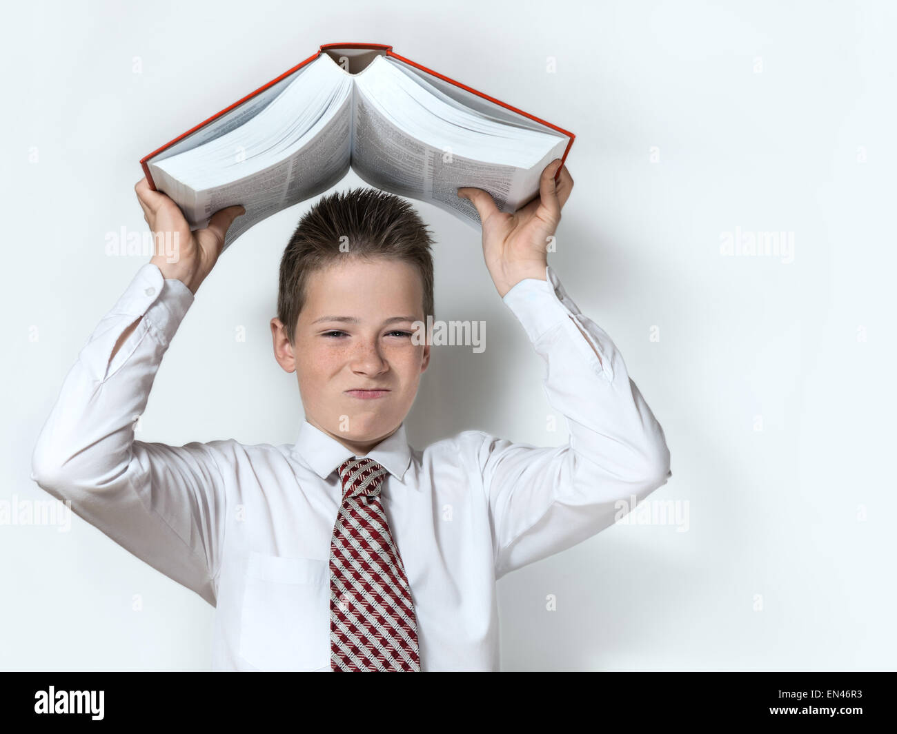 Schuljunge wirft große rote Buch unzufrieden Stockfoto