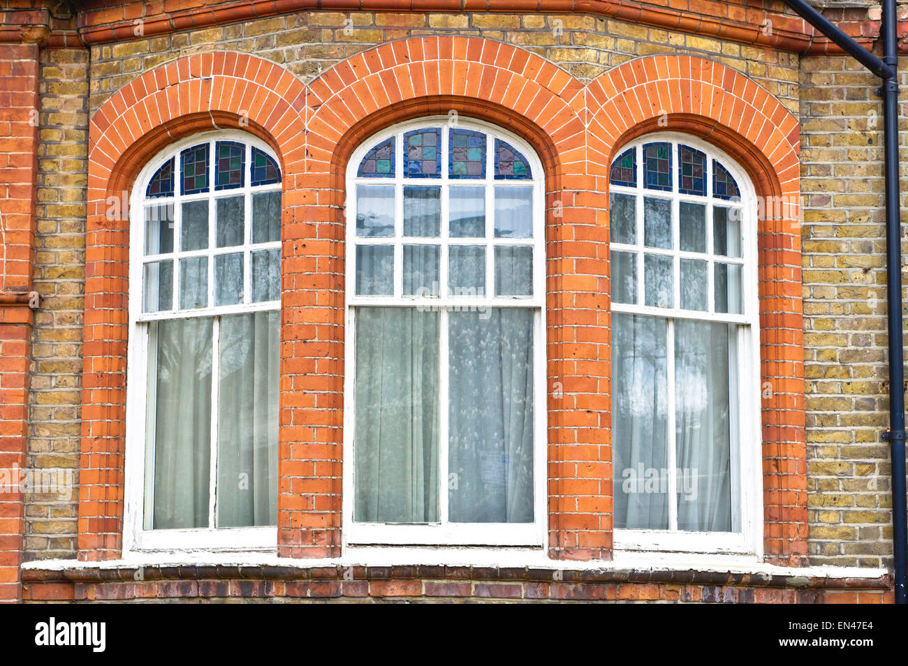 Bogenfenster in einem roten Backsteingebäude in London, Großbritannien Stockfoto