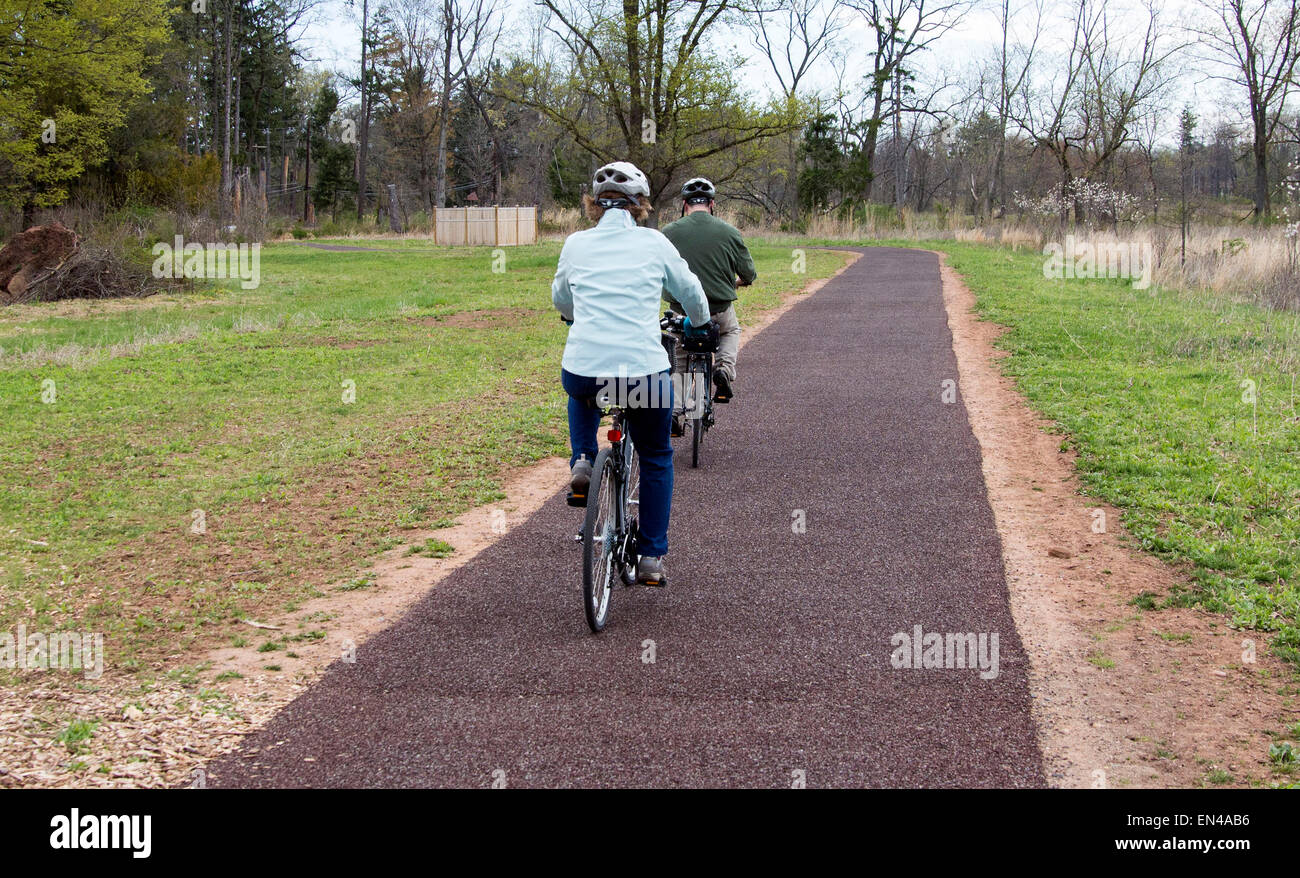 Paar senior Mann und Frau auf Fahrrädern auf einem gepflasterten Weg in den Park. Stockfoto