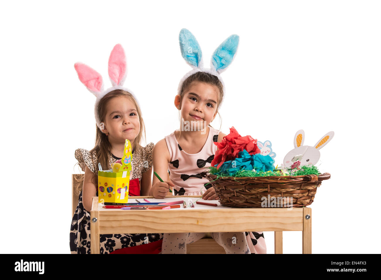 Zwei Mädchen mit Hase Ohren bemalen von Ostereiern und machen ein schiefes Gesicht und sitzen zusammen am Tisch Stockfoto