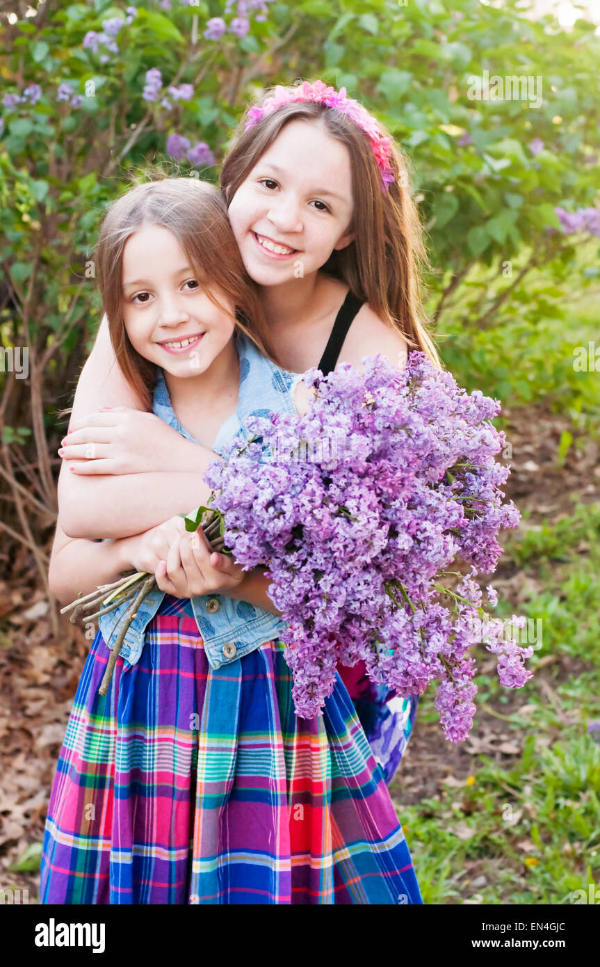 Zwei Mädchen umarmen Holding lila Blumenstrauß Stockfoto