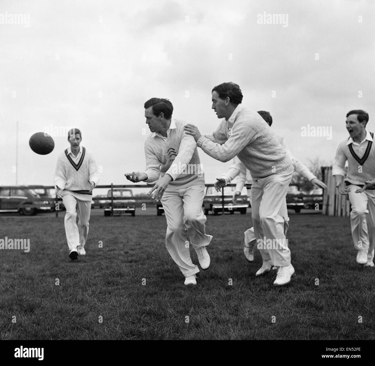 Lockerungsübungen mit einem Rugby-Ball sind Essex Cricket Teammitglieder Ken Preston (Mitte) in Angriff genommen von Gill Greensmith (rechts)) während einer Rtainimg-Sitzung im alten Blues R.F Club Boden in Fairlop, Essex. 22. April 1963. Stockfoto