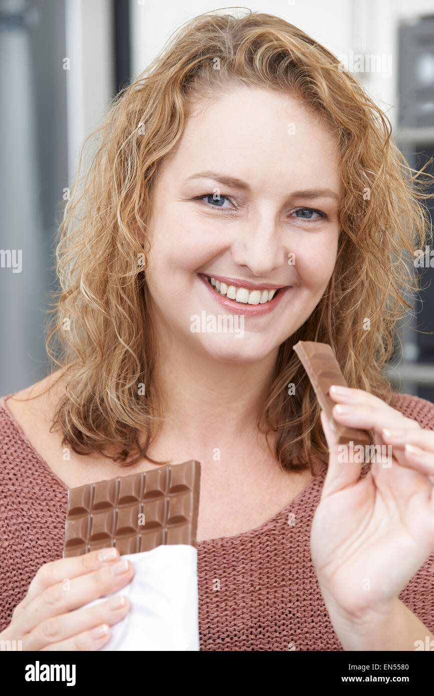 Lächelnd Plus Size Frau Bar Schokolade essen Stockfoto
