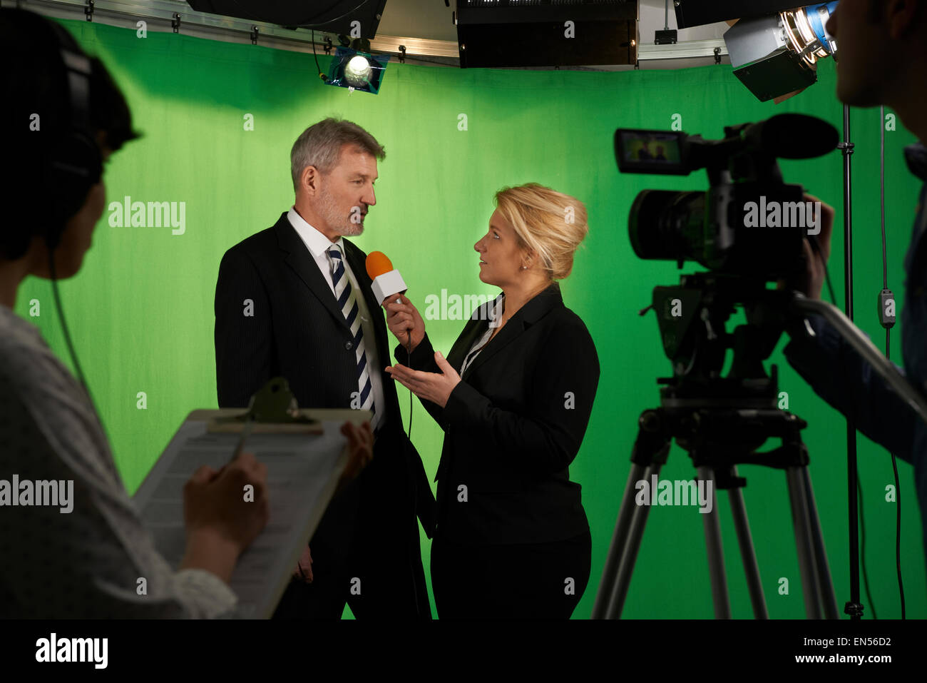 Weibliche Moderatorin interviewt im Fernsehstudio mit Crew im Vordergrund Stockfoto
