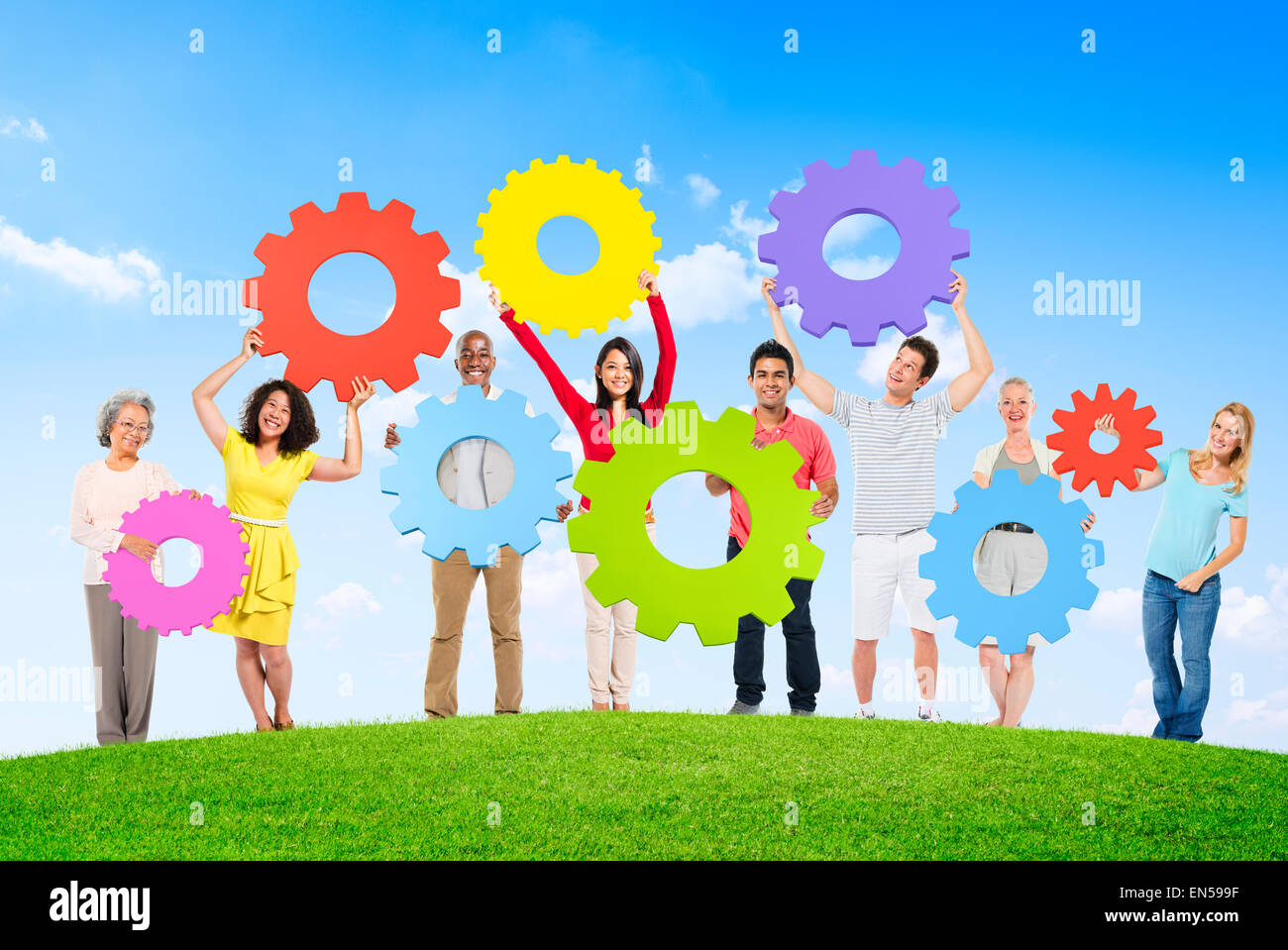 Diverse Leute draußen halten Zahnräder Stockfoto